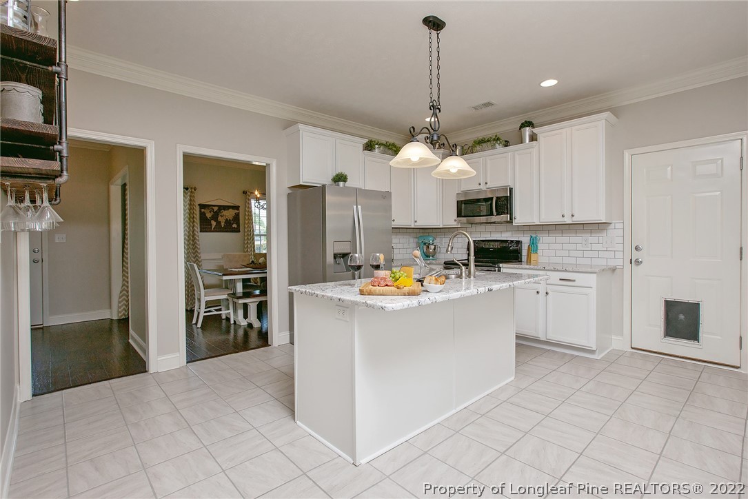 71 Germantown Road Cameron, NC 28326 - Photo 12 of 36 a kitchen view with stainless steel appliances a stove a refrigerator and white cabinets