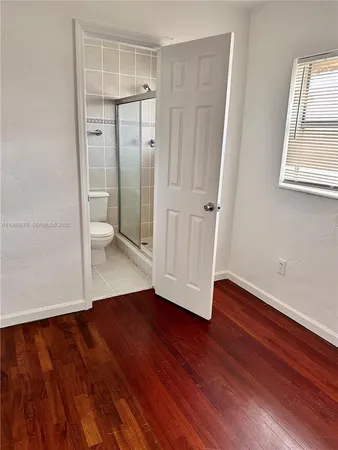 an empty room with wooden floor and a bathroom