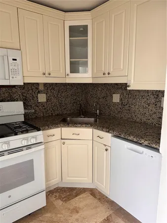 a kitchen with granite countertop white cabinets and stainless steel appliances