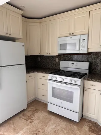 a kitchen with white cabinets and white appliances