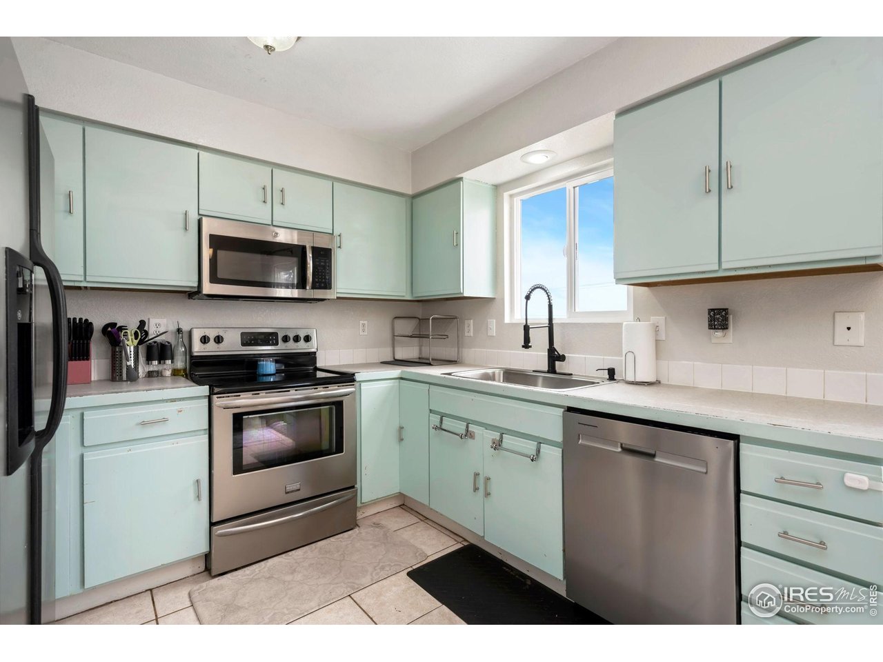 1113 East 24th Street Road Greeley, CO 80631 - Photo 7 of 25 a kitchen with stainless steel appliances granite countertop a sink a stove a microwave and cabinets