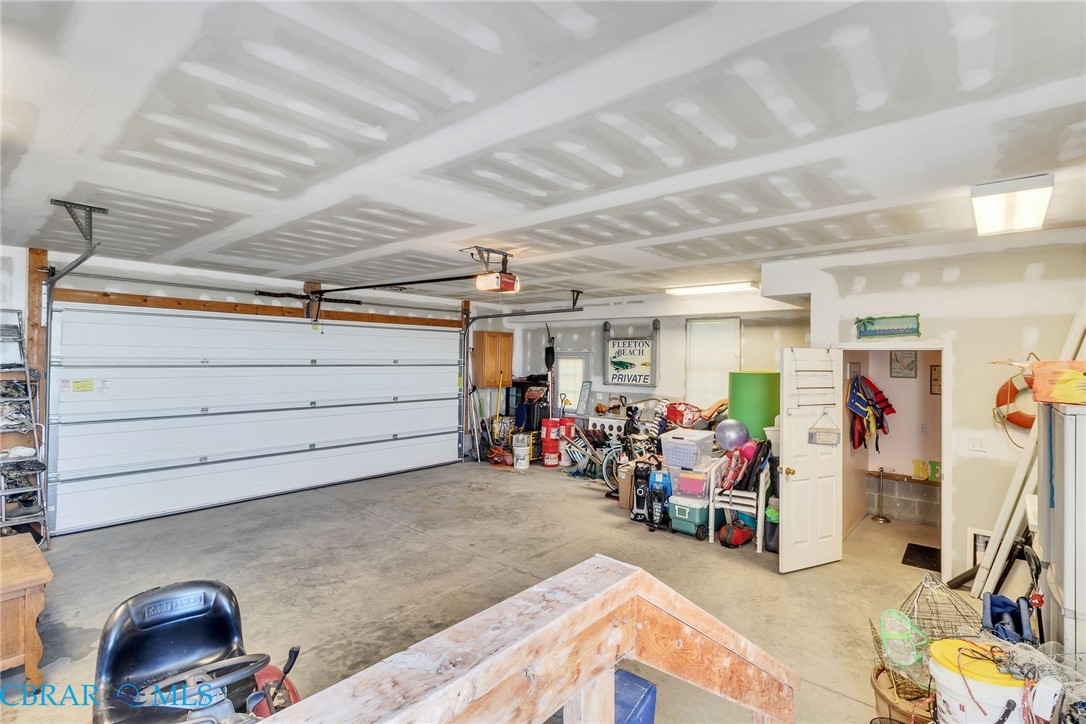13 Leming Avenue Reedville, VA 22539 - Photo 42 of 50 Spacious garage featuring a concrete floor, two white overhead doors with automatic openers, and exposed ceiling joists