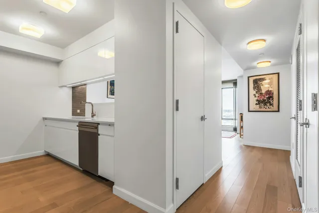 a view of a kitchen from the hallway with a white stove top oven and wooden floor