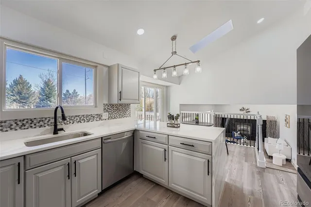 a kitchen with a sink dishwasher a stove and white cabinets with wooden floor