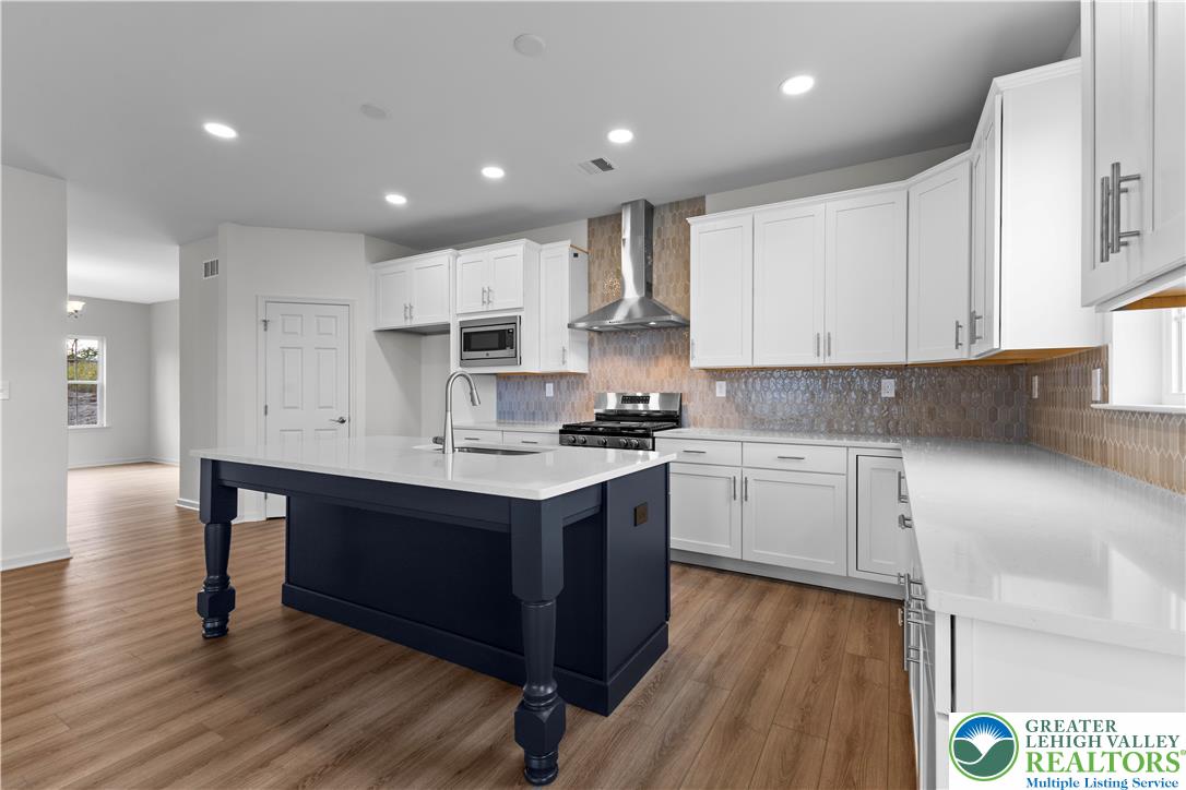 4929 Farrcroft Drive, Unit 83B Easton, PA 18040 - Photo 5 of 30 a kitchen with kitchen island wooden floors white cabinets and appliances