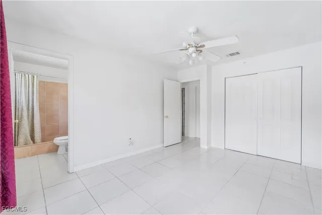 an empty room with chandelier fan and closet