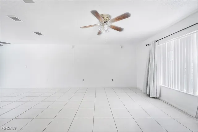 an empty room with white walls and ceiling fan