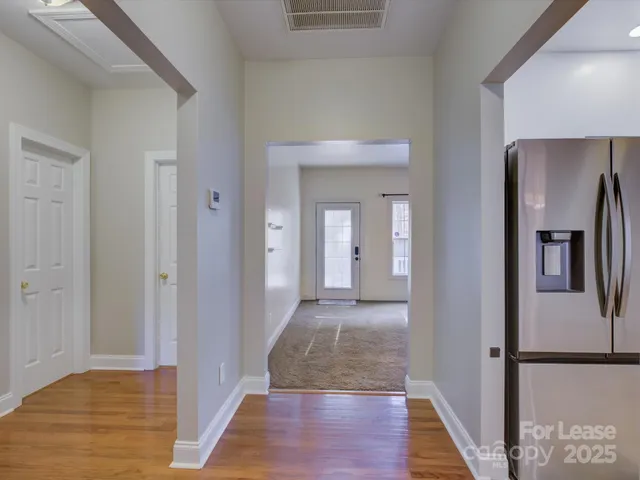a view of a hallway with wooden floor and a bathroom