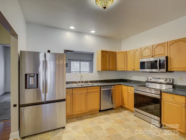 a kitchen with stainless steel appliances granite countertop a refrigerator sink stove microwave and cabinets