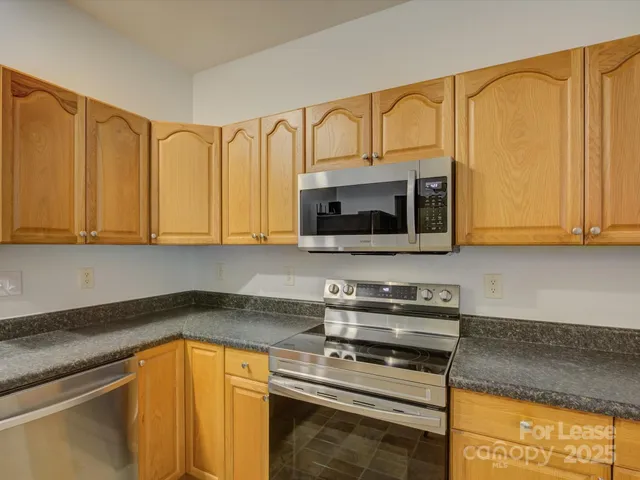 a kitchen with stainless steel appliances granite countertop a stove microwave and cabinets