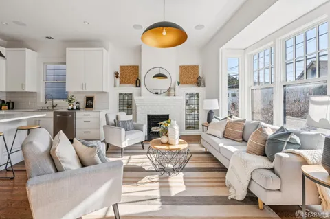 a kitchen with kitchen island stainless steel appliances a dining table chairs sink and cabinets