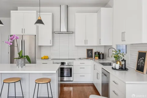 a kitchen with a sink dishwasher a stove and white cabinets