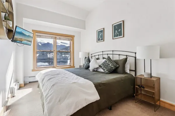 a bedroom with a bed and a flat tv screen on the dresser