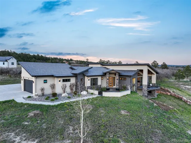a front view of a house with a garden and trees