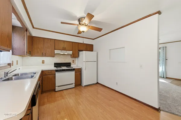 a kitchen with stainless steel appliances granite countertop a refrigerator a sink dishwasher a stove with white cabinets and wooden floor