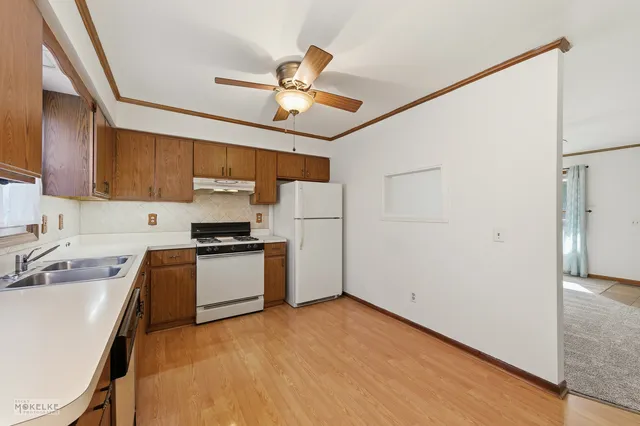 a kitchen with stainless steel appliances granite countertop a refrigerator a sink dishwasher a stove with white cabinets and wooden floor