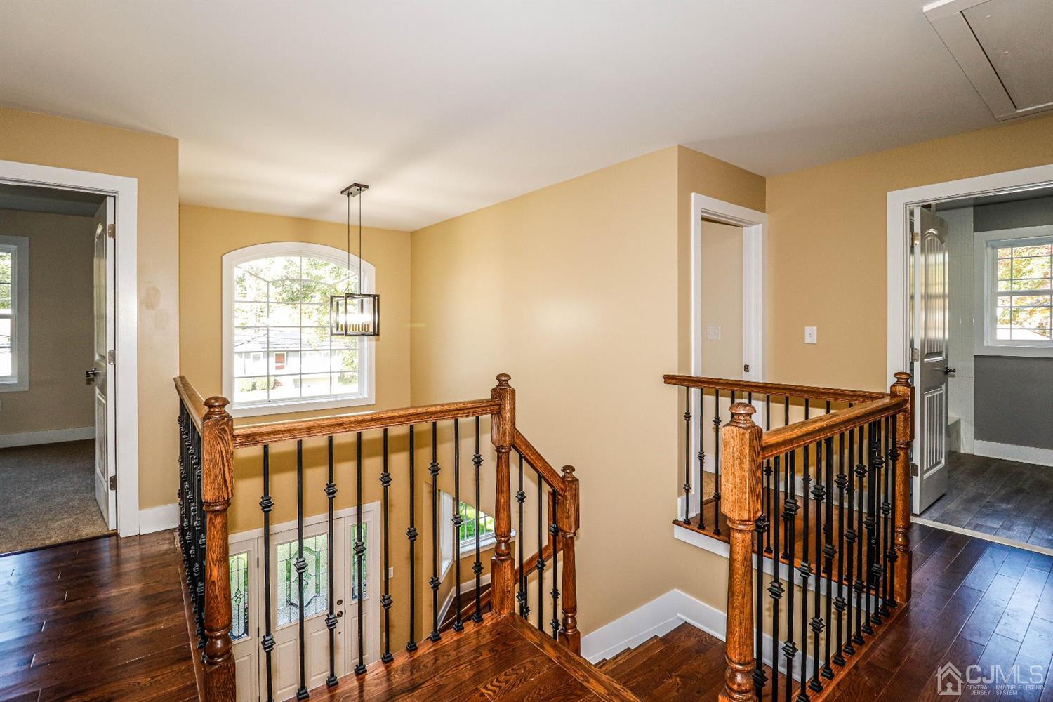 1834 Oak Road North Brunswick, NJ 08902 - Photo 20 of 39 Hallway on upper level of this upscale home. Features wood floors, Palladian window and wood railing. The pull down steps leading to the attic are located in this hall area.