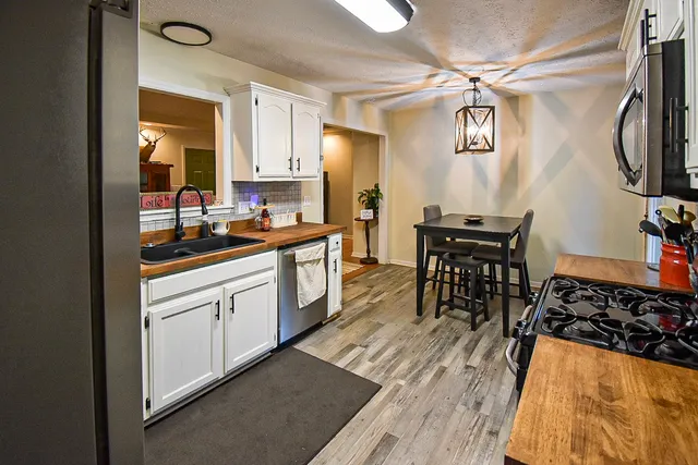 a kitchen with stainless steel appliances a table and chairs in it