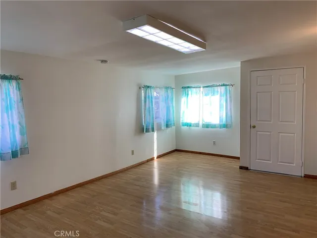 an empty room with wooden floor cabinet and windows