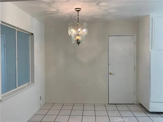 a view of an empty room with chandelier fan