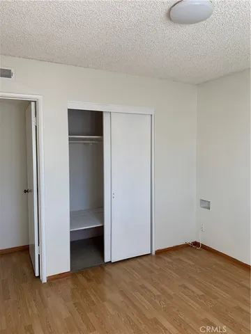 a view of an empty room with wooden floor and closet