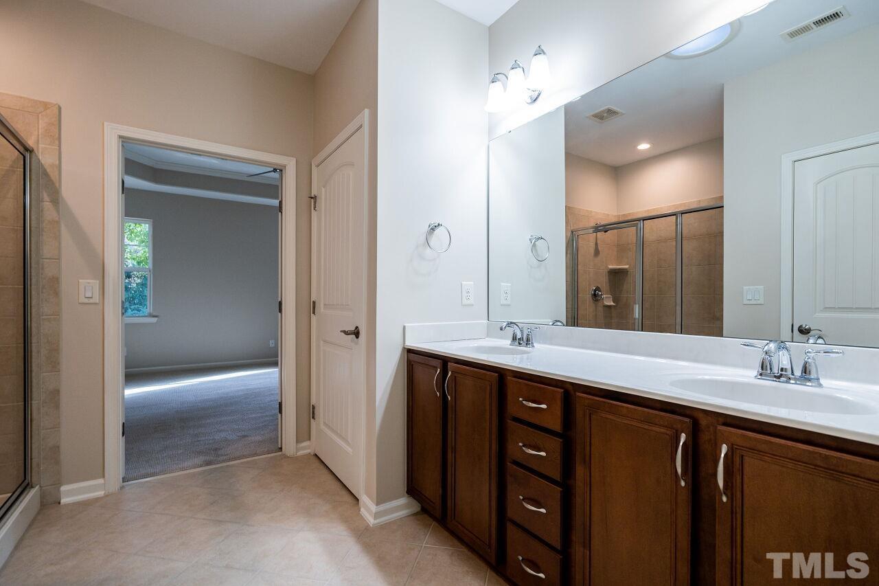 4713 Gaelic Trail Raleigh, NC 27604 - Photo 21 of 26 a spacious bathroom with a double vanity sink a large mirror and a bathtub