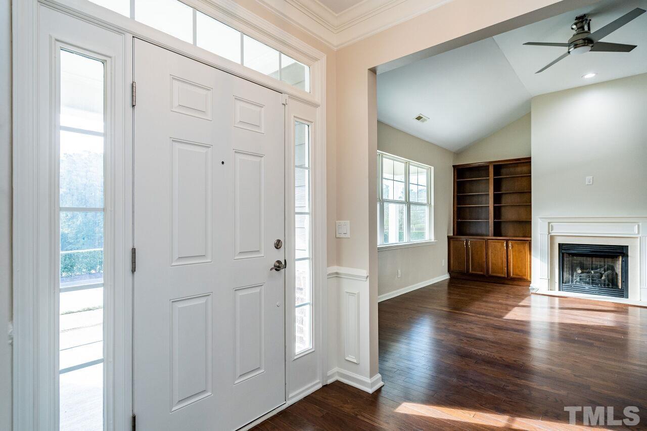 4713 Gaelic Trail Raleigh, NC 27604 - Photo 4 of 26 an empty room with wooden floor fireplace and windows