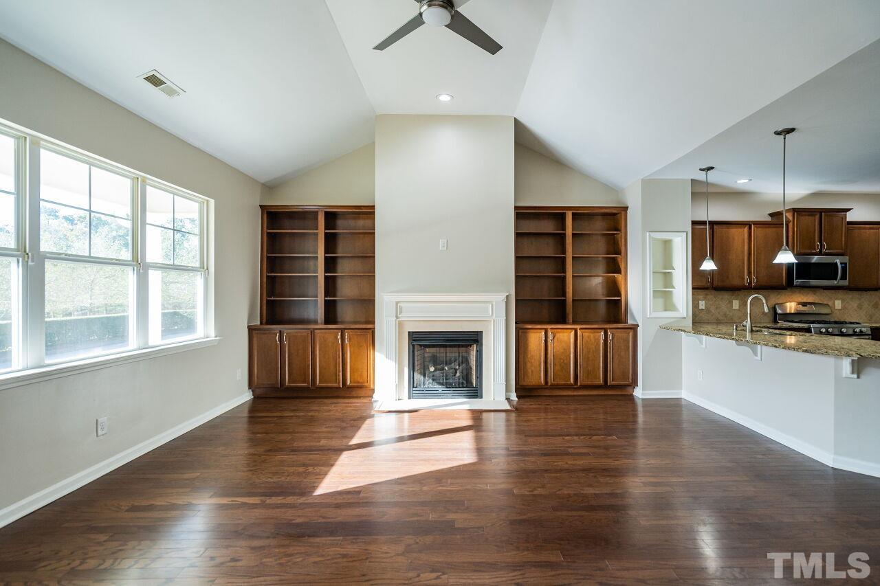 4713 Gaelic Trail Raleigh, NC 27604 - Photo 6 of 26 an empty room with wooden floor a kitchen view and a fireplace