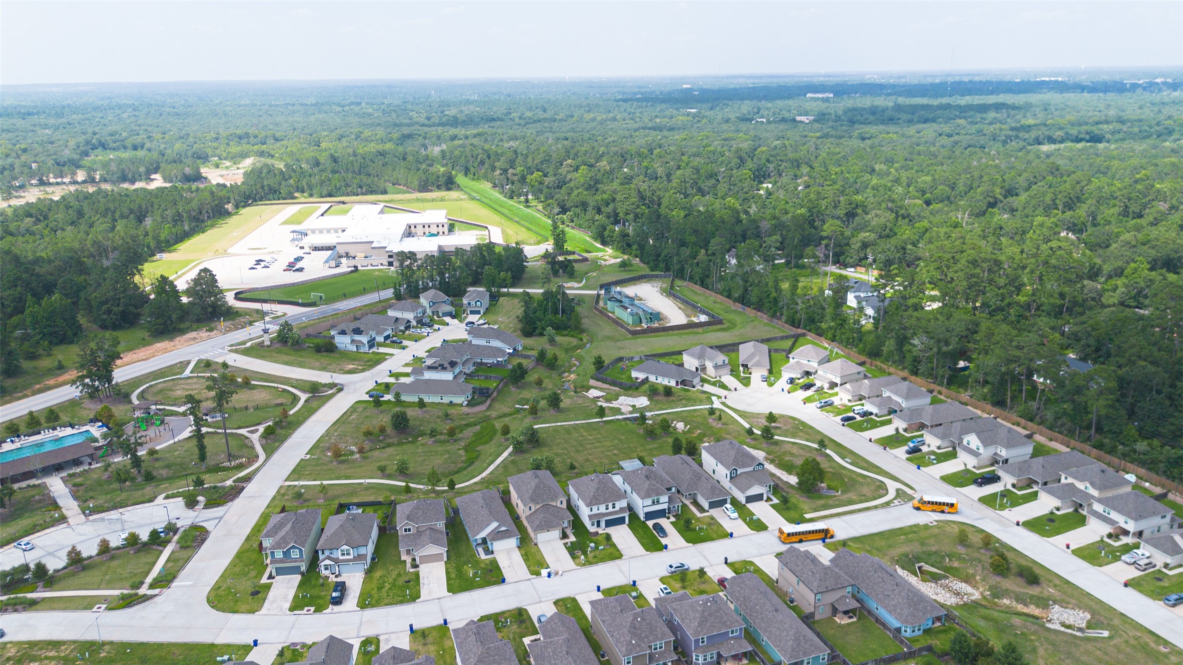 2526 Sturgeon Way Conroe, TX 77384 - Photo 48 of 49 This aerial photo showcases a serene neighborhood with modern homes, well-maintained lawns, and winding streets. It’s surrounded by lush greenery, providing a peaceful setting. Nearby amenities include a school and recreational facilities, making it ideal for families.