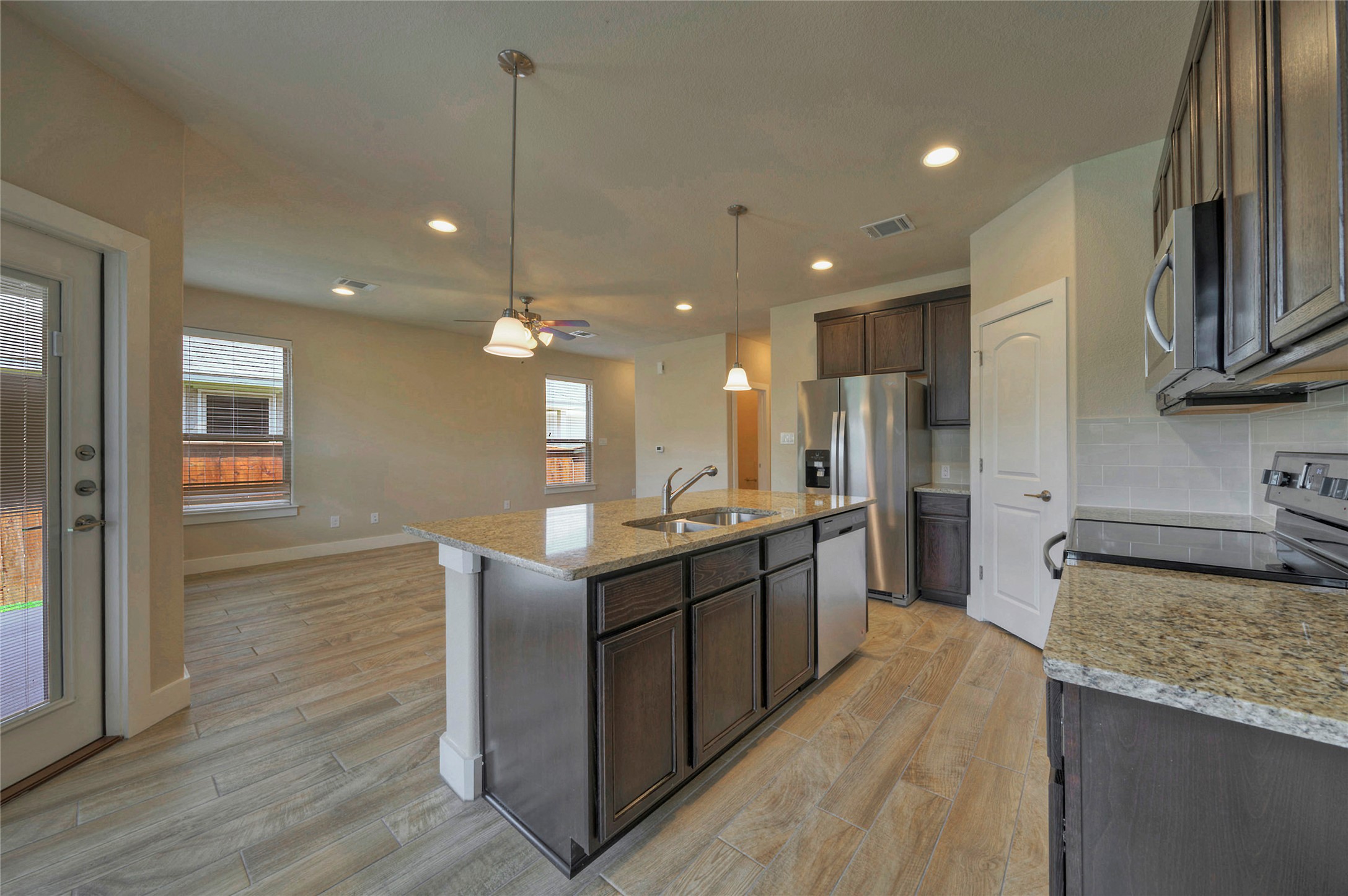 508 High Tech Drive, Unit B Georgetown, TX 78626 - Photo 7 of 24 An inviting open-concept kitchen features a spacious island with granite countertops and modern appliances, seamlessly flowing into the living area.