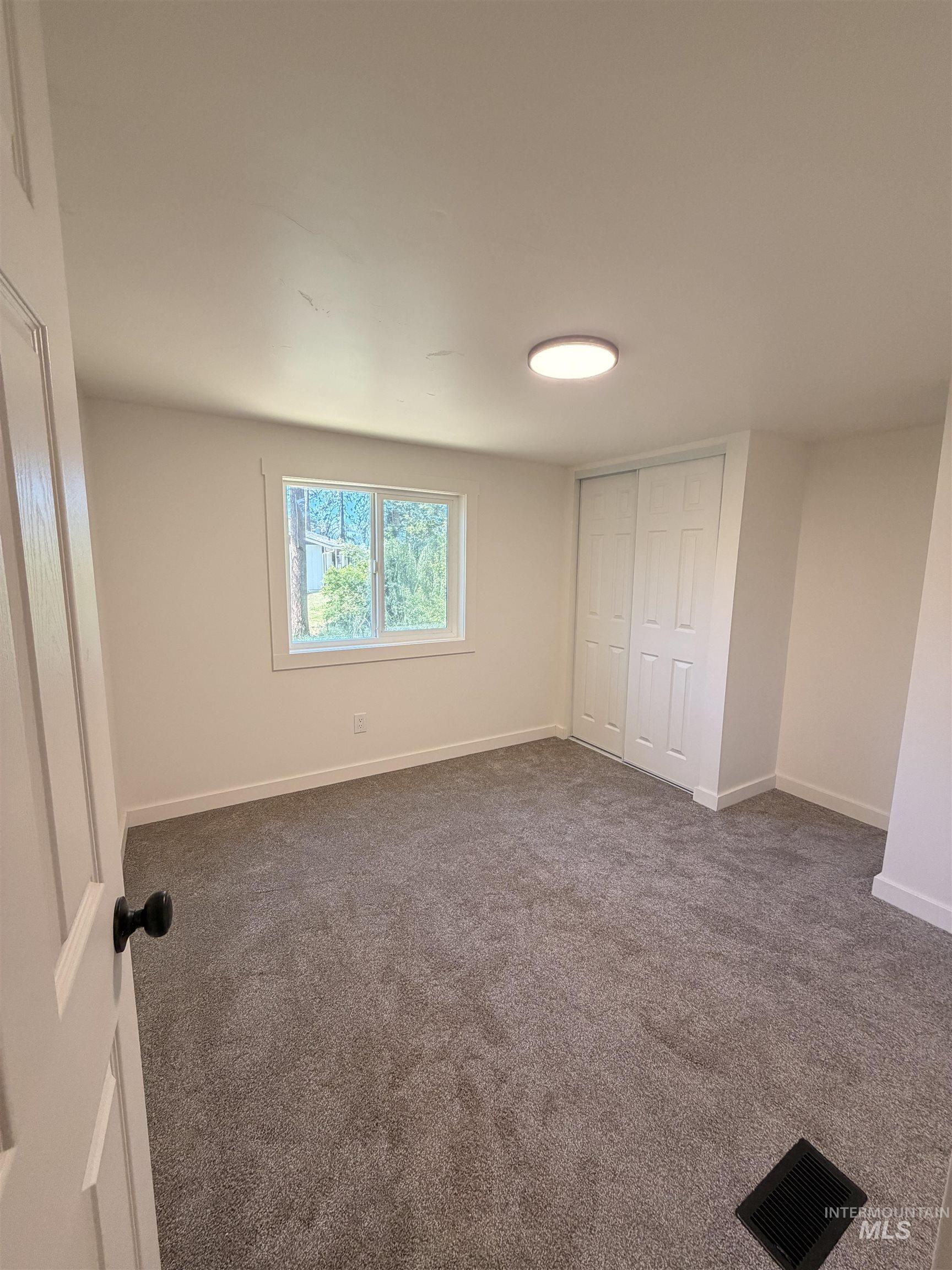151 View Road Kamiah, ID 83536 - Photo 25 of 49 Carpeted room featuring a double-pane window with white trim, white walls, and a flush-mount ceiling light