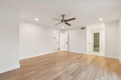 a view of empty room with wooden floor and ceiling fan