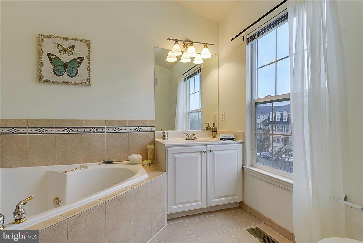 11344 King George Drive, Unit 5 Silver Spring, MD 20902 - Photo 22 of 30 a bathroom with a granite countertop tub a sink and a large mirror