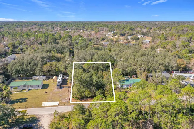 an aerial view of residential houses with outdoor space and trees