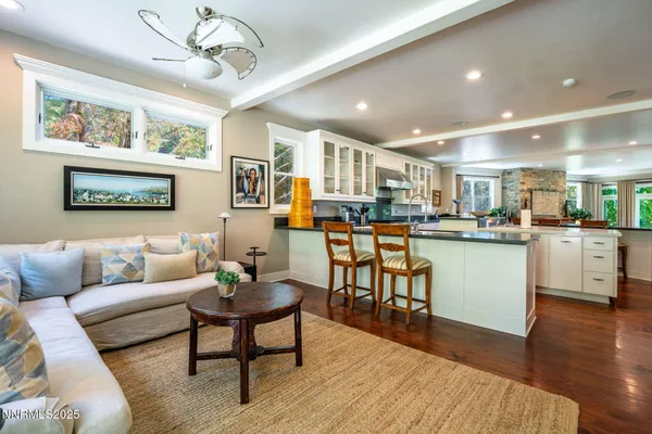 a living room with stainless steel appliances kitchen island granite countertop furniture wooden floor and a large window