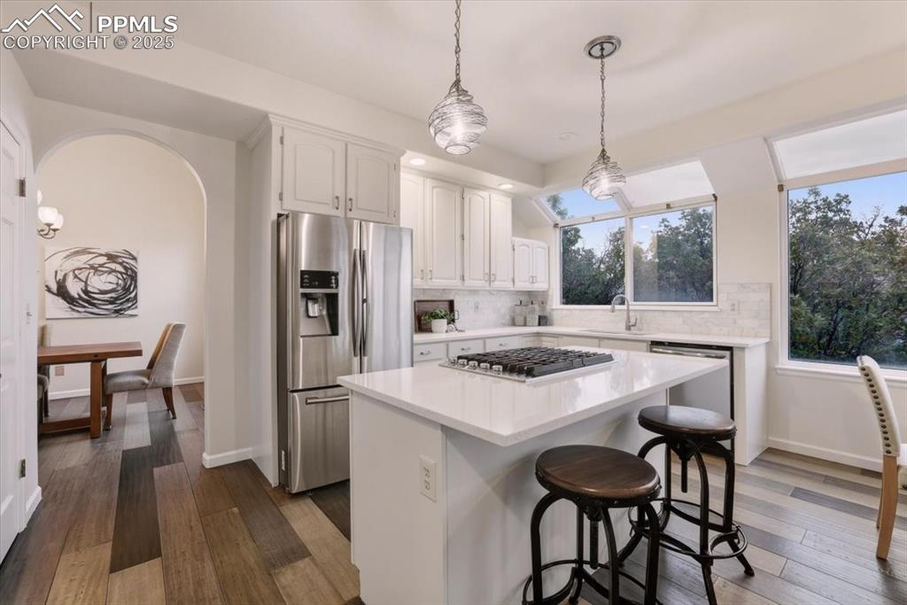 395 Cardiff Circle Colorado Springs, CO 80906 - Photo 7 of 31 a kitchen with stainless steel appliances granite countertop a stove a refrigerator a oven a white table and chairs with wooden floor