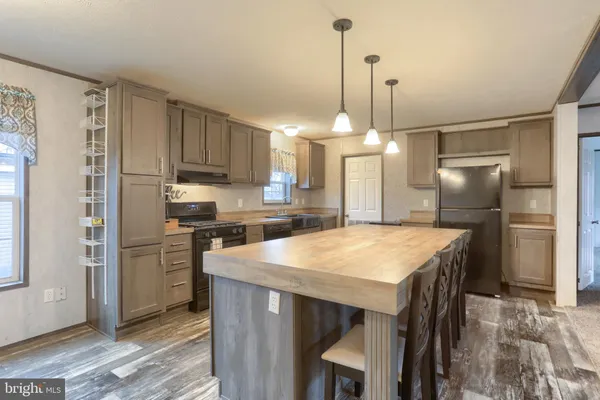 a kitchen with kitchen island a stove a refrigerator a sink a dining table and chairs