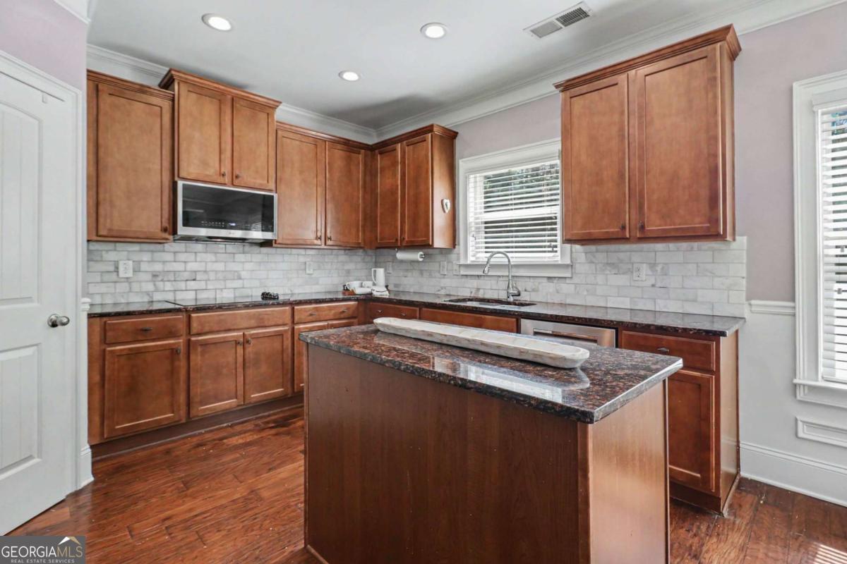 207 George Wynn Road Palmetto, GA 30268 - Photo 13 of 32 a kitchen with stainless steel appliances granite countertop a stove a sink dishwasher and a microwave oven with wooden floor