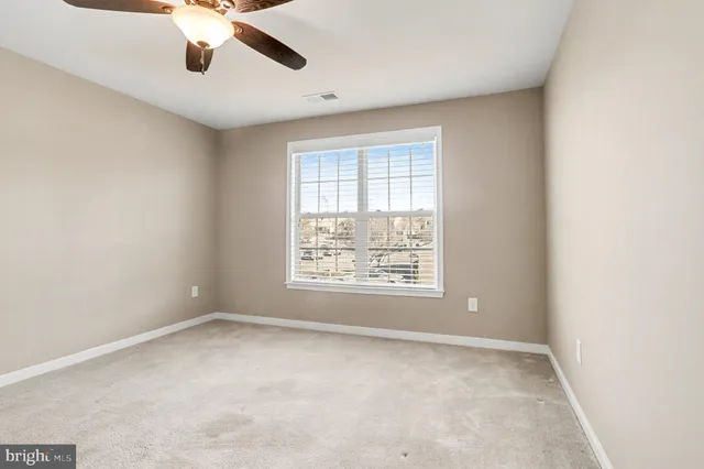 an empty room with a window and a fan