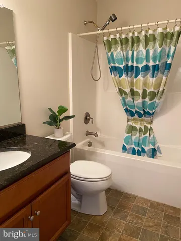 a bathroom with a granite countertop sink a toilet a mirror and shower