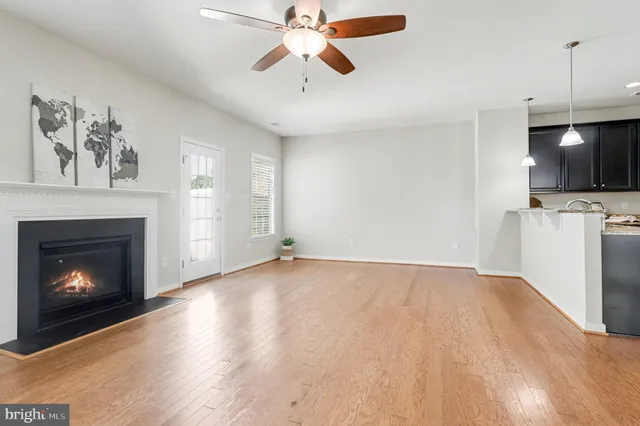 a view of a livingroom with a fireplace a ceiling fan and a hardwood floor