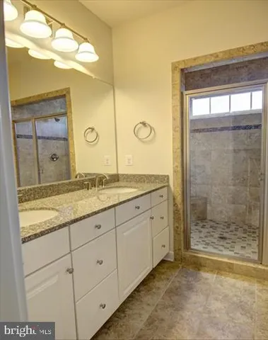 a bathroom with a granite countertop sink a mirror and a shower