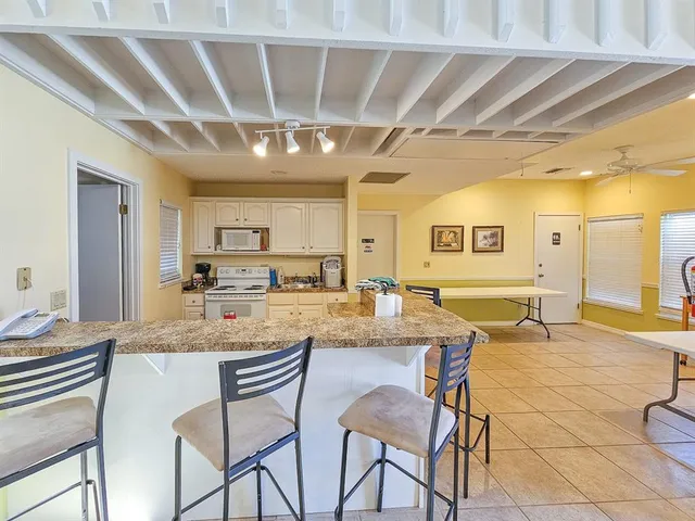 a dining hall with stainless steel appliances granite countertop a sink and cabinets