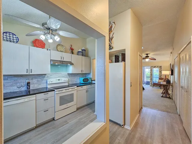 a kitchen with a sink dishwasher a stove and white cabinets with wooden floor