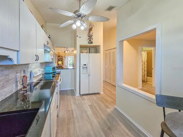 a kitchen with stainless steel appliances granite countertop a refrigerator a sink dishwasher a stove and white countertops with wooden floor