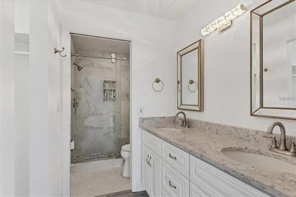 a bathroom with a granite countertop sink a mirror and a shower