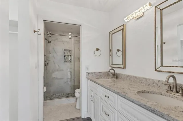 a bathroom with a granite countertop sink a mirror and a shower