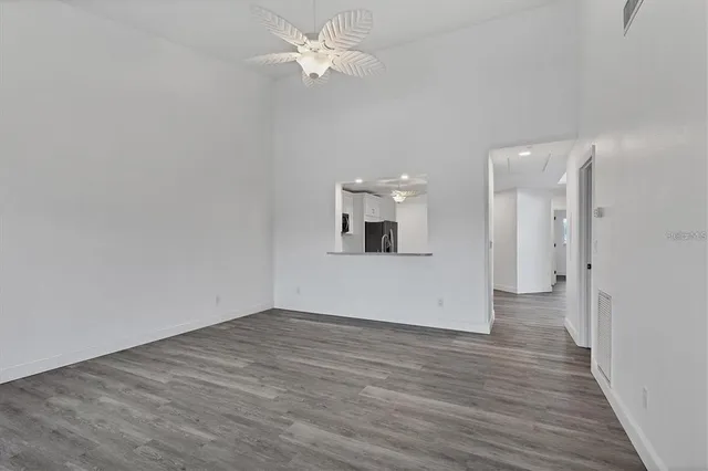 an empty room with wooden floor and ceiling fan