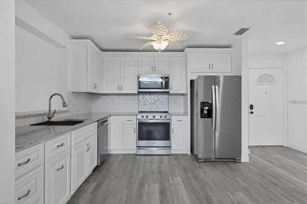 a kitchen with stainless steel appliances granite countertop a refrigerator and a stove top oven