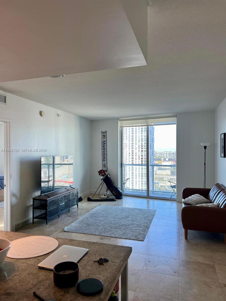 185 Southwest 7th Street, Unit 2601 Miami, FL 33130 - Photo 5 of 17 a living room with furniture and a flat screen tv